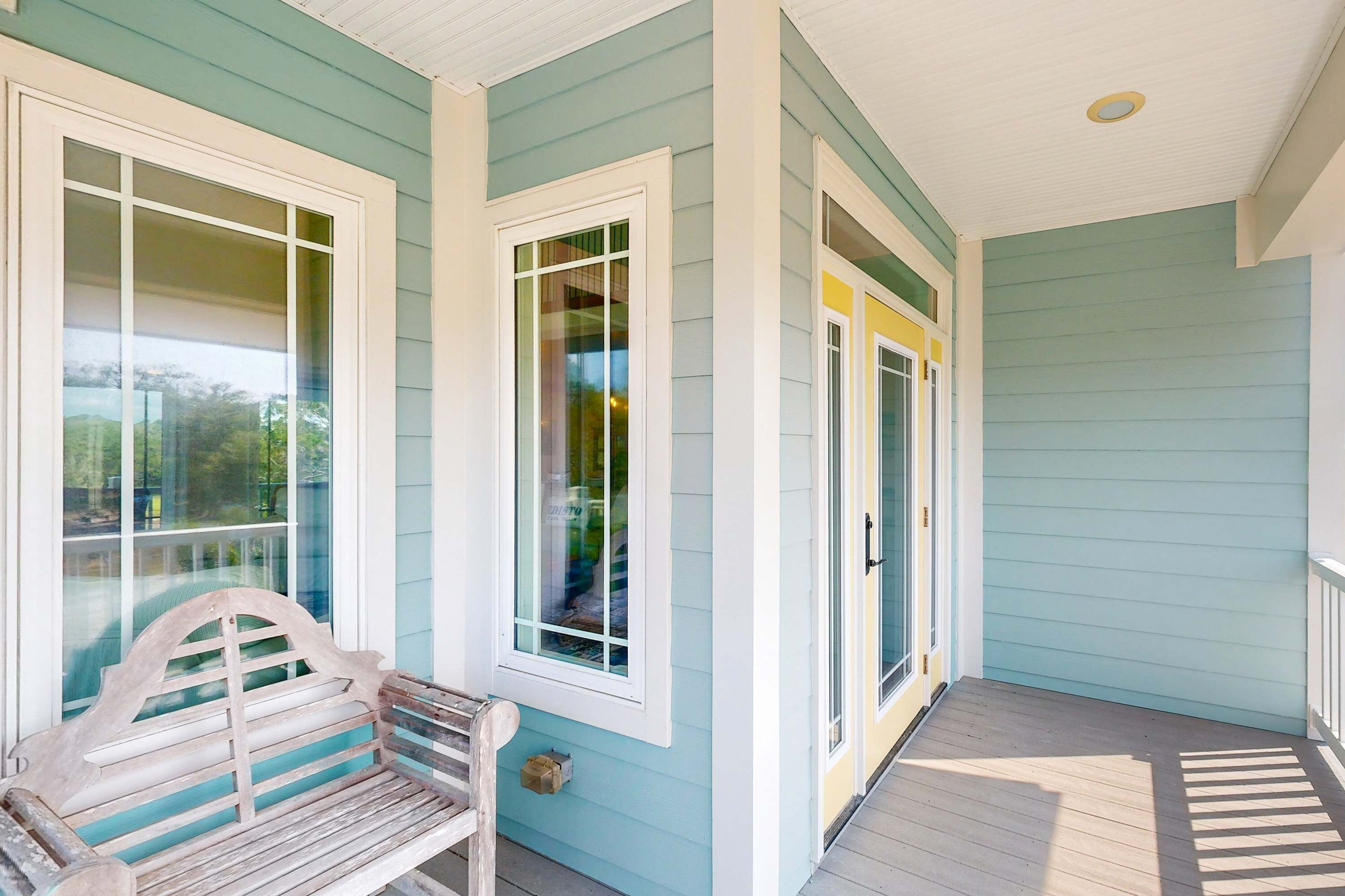 A porch with a wooden bench, a door, and a window.