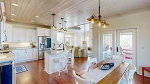 A spacious kitchen with wooden flooring, white cabinetry, and pendant lighting. - Coastal home- Marsh Views with open floor plan and stunning sunsets (Edisto Island)