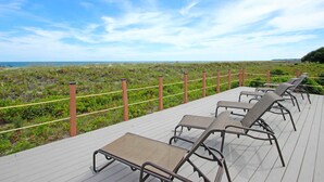 A deck with lounge chairs overlooking a beach. - Oceanfront villa with WiFi, full kitchen, pool, & hot tub - beach nearby (Hilton Head)