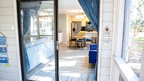 Una porta a vetri scorrevoli conduce in una stanza con zona pranzo, cucina e vista sull'esterno.