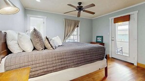 Un dormitorio con cama, ventilador de techo y vista por una puerta.