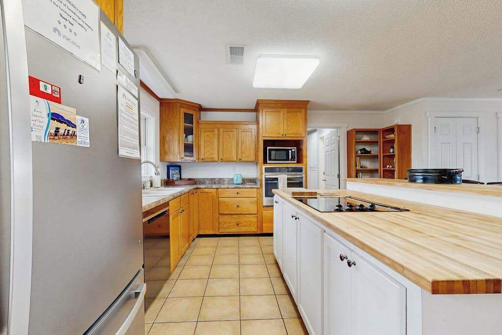 A kitchen with wooden cabinets, a microwave, an oven, and a sink.