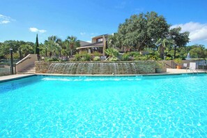 Une piscine avec un mur en pierre et des marches menant à un bâtiment.