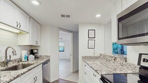 A modern kitchen with white cabinets, granite countertops, stainless steel appliances, and recessed ceiling lights. - Newly renovated villa near the beach with pool & tennis  walk to Coligny Plaza (Hilton Head)
