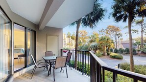 A balcony with a table and chairs, a view of the street, and palm trees. - Newly renovated villa near the beach with pool & tennis  walk to Coligny Plaza (Hilton Head)