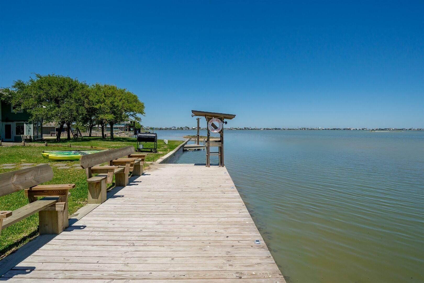 Une jetée en bois menant à un quai, avec un kiosque et des bancs disposés le long.