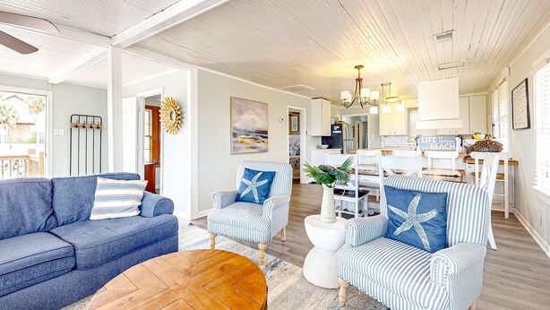 A spacious living area with a blue sofa, striped armchairs, and a wooden coffee table. - Beautiful home across from the sea with balcony & open layout - dog-friendly (Edisto Beach)