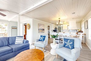 A spacious living area with a blue sofa, striped armchairs, and a wooden coffee table. - Beautiful home across from the sea with balcony & open layout - dog-friendly (Edisto Beach)