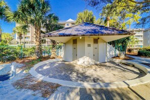 A small building with a curved roof, surrounded by a paved area and palm trees. - Beach access condo with deck, pool, washer dryer, and AC - snowbird-friendly (Hilton Head)