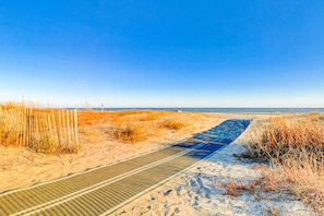 A sandy beach path leading to the ocean, with a wooden fence and dry grass on the left. - Dunes Villas D2  Villa w pool, beach access (Hilton Head)