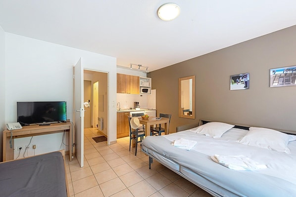Une chambre d’hôtel comprenant un lit, un bureau avec une télévision, une kitchenette et une salle de bain.