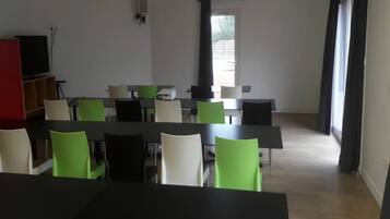 Una sala conferenze con tavoli e sedie, un televisore e una porta che dà sull'esterno.