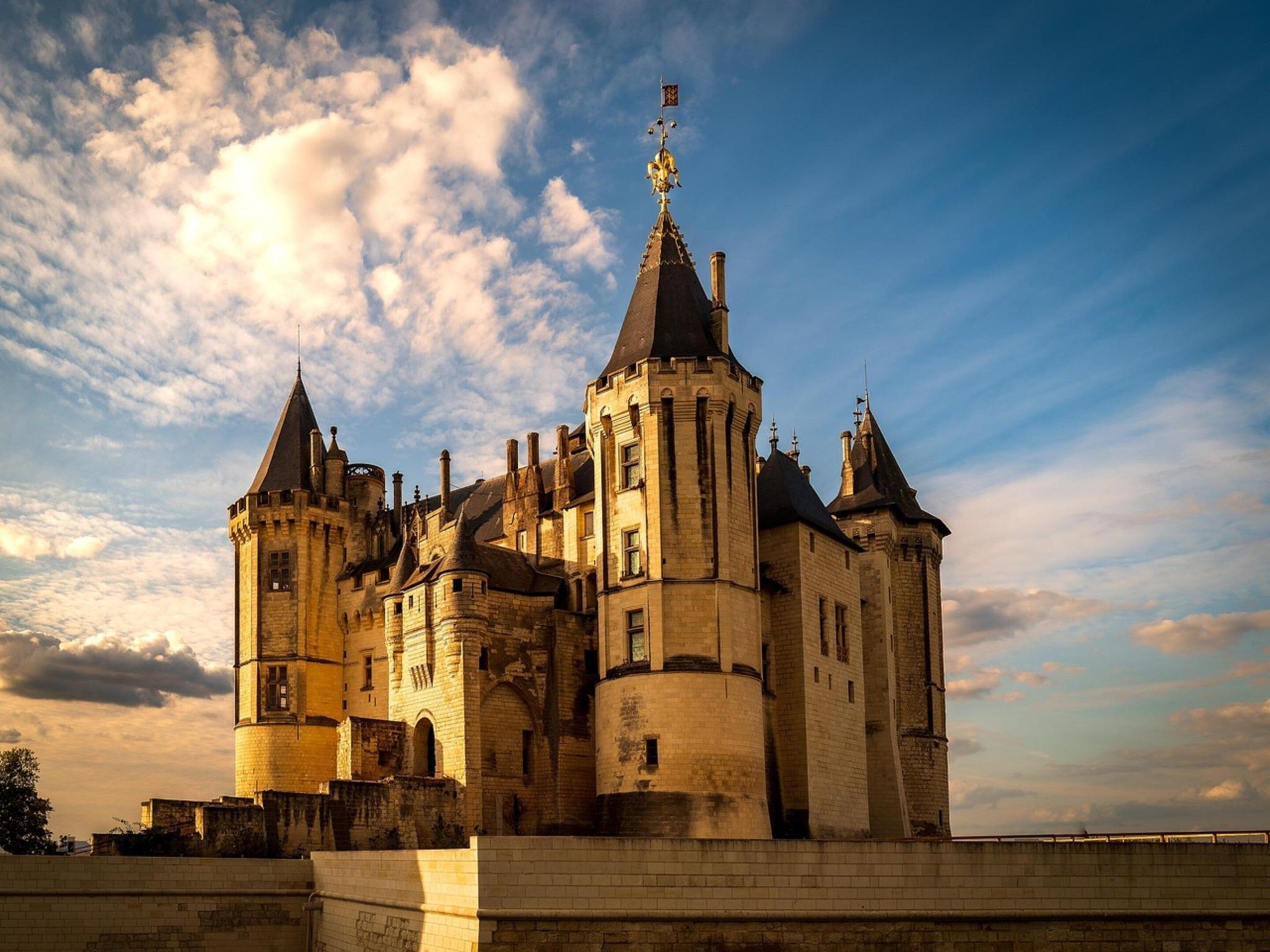 A historic castle with multiple towers and a prominent flag on top.