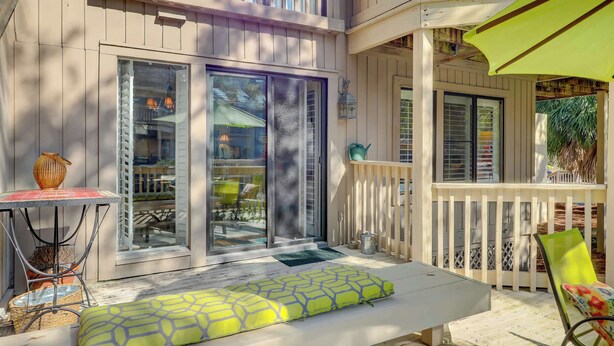 A covered outdoor area with a table, chairs, and a bench. - Coastal Villa with Spacious Deck, Pool & Walk to Beach (Hilton Head)