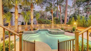 A swimming pool with a brick border and palm trees, surrounded by a wooden fence. - Luxurious home with private pool, central AC, & high-speed WiFi - walk to beach (Hilton Head)
