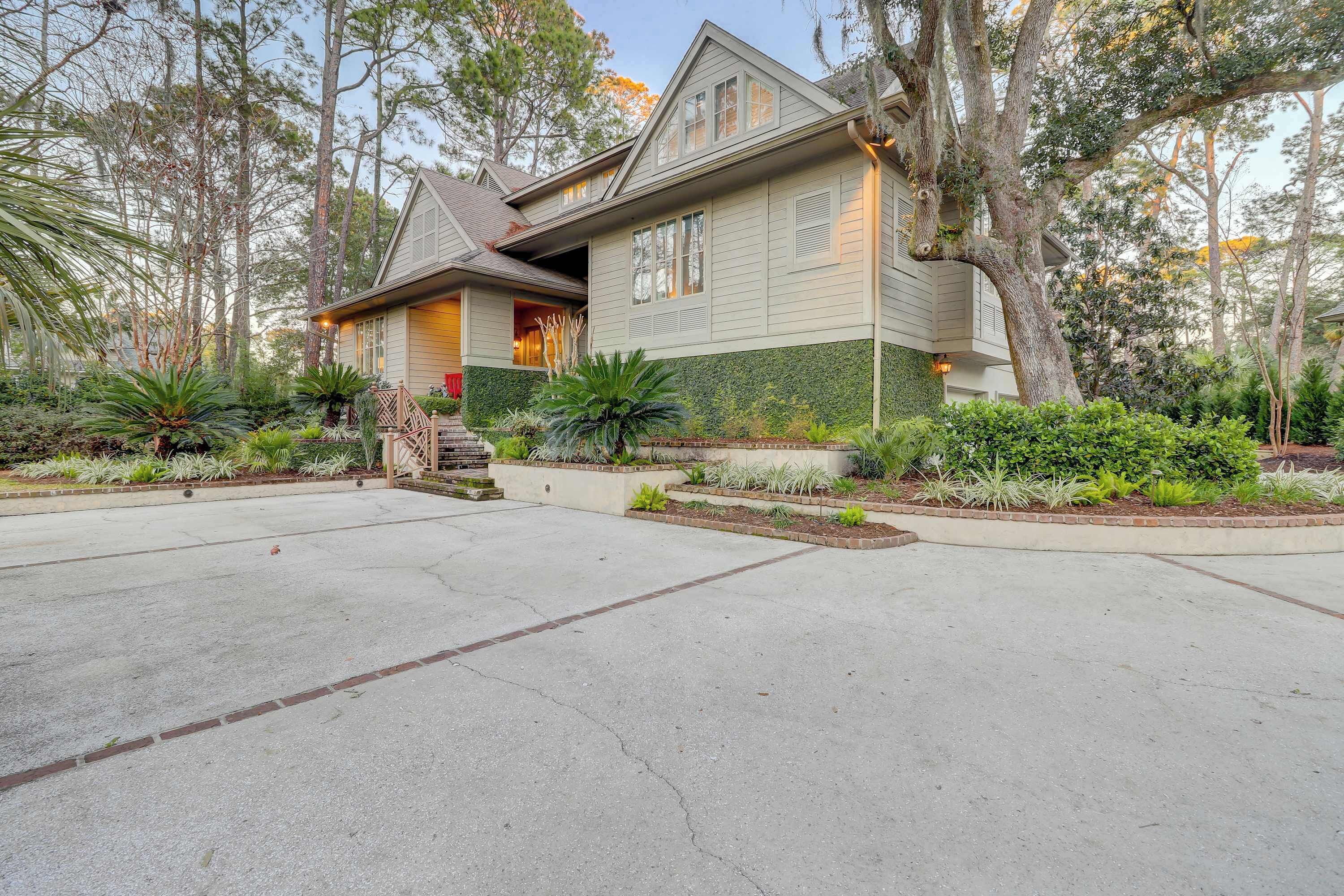 A two-story house with a front porch, surrounded by a landscaped garden with various plants and trees.