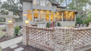 A two-story house with a brick wall, a covered porch, and a staircase leading to the upper level. - Luxurious home with private pool, central AC, & high-speed WiFi - walk to beach (Hilton Head)