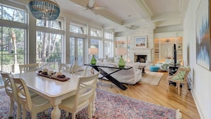A spacious living area with a dining table, chairs, a fireplace, and large windows. - Luxurious home with private pool, central AC, & high-speed WiFi - walk to beach (Hilton Head)