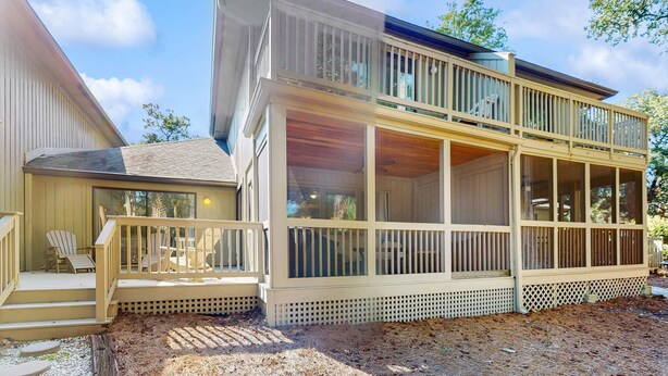 Ein zweistöckiges Haus mit überdachter Veranda, einer Terrasse und einer großen, raumhohen Fensterfront.