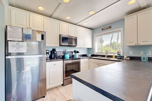 A modern kitchen with stainless steel appliances, white cabinetry, and a large island.