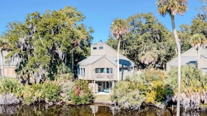Ein Haus mit Veranda, umgeben von Bäumen und einem Teich.