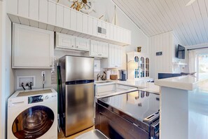 A modern kitchen with white cabinetry, stainless steel appliances, and a built-in dishwasher.