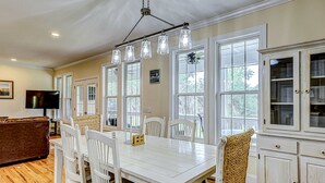 A dining area with a white table, chairs, and a hanging light fixture. - Beautiful home near the beach with beach access, central AC, & washer/dryer (Edisto Beach)