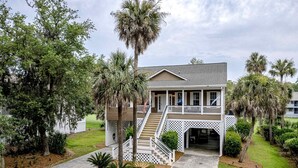 A two-story house with a porch, a staircase, and a covered entryway. - Beautiful home near the beach with beach access, central AC, & washer/dryer (Edisto Beach)