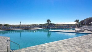 Ein rechteckiger Pool mit gefliestem Sonnendeck und Liegestühlen.