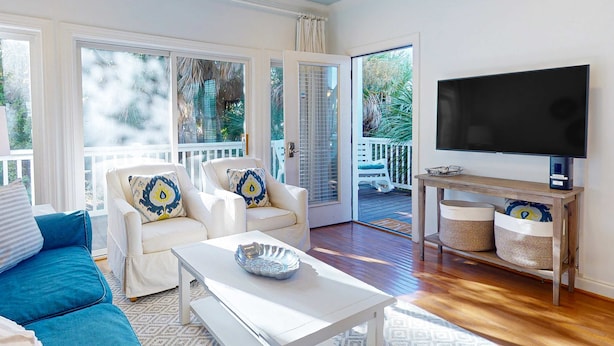 A living room with a sofa, armchair, coffee table, TV, and a balcony with a view. - Sea Sea Rider (Edisto Beach)