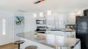Une cuisine moderne dotée d’un îlot central, de luminaires suspendus et d’un réfrigérateur.