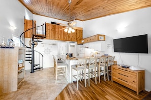 A modern kitchen with a wooden ceiling, a spiral staircase, and a dining area with white chairs. - 3rd-floor, dog-friendly condo with loft, balcony, free WiFi and golf course view (Edisto Beach)