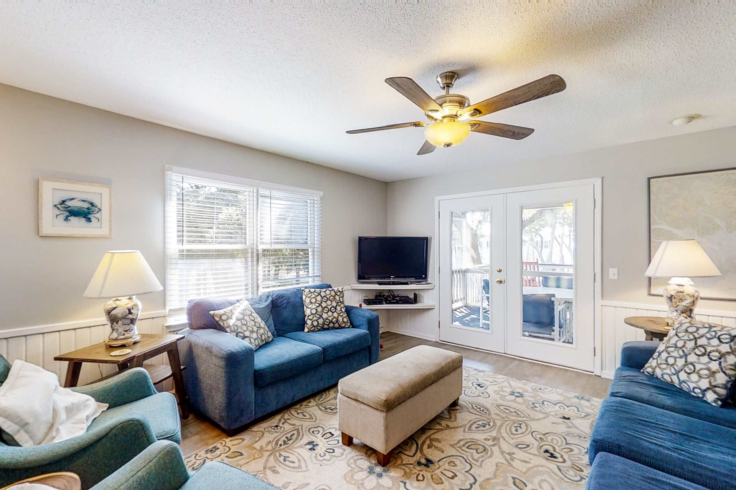 A living room with a ceiling fan, a television, and a patterned rug.