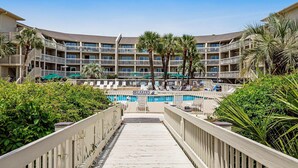 A hotel with multiple balconies, a swimming pool, and lush greenery. - Condo with Coligny Beach views, outdoor pool, beach access, balcony, WD, & AC (Hilton Head)