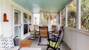 A covered porch with a dining table and chairs, a rocking chair, and a sofa with patterned pillows. - Newly Renovated, Dog-Friendly Home w/ Ocean View, Decks, WiFi - Walk to Beach (Edisto Beach)