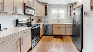 A modern kitchen with stainless steel appliances, wooden flooring, and light-colored cabinetry. - Newly Renovated, Dog-Friendly Home w/ Ocean View, Decks, WiFi - Walk to Beach (Edisto Beach)