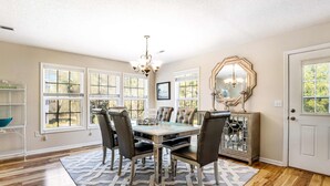 A dining room with a chandelier, a large mirror, and a dining table with chairs. - Bay view home three blocks to the beach with WiFi, central AC, and private w/d (Edisto Beach)