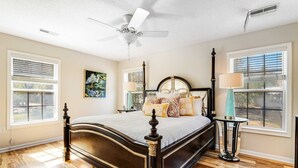 A bedroom with a four-poster bed, a ceiling fan, and a nightstand with a lamp. - Bay view home three blocks to the beach with WiFi, central AC, and private w/d (Edisto Beach)