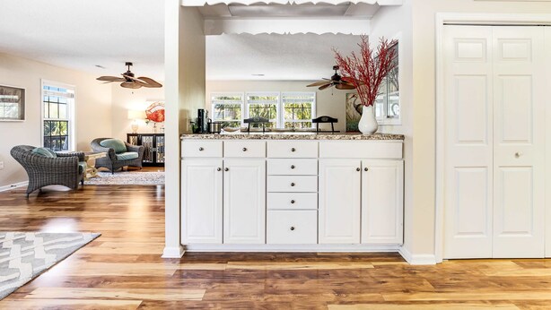 A kitchen with white cabinets, a ceiling fan, and a view of the outdoors. - Bay view home three blocks to the beach with WiFi, central AC, and private w/d (Edisto Beach)
