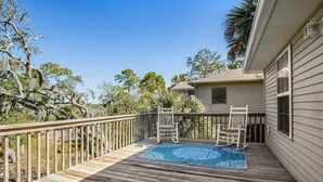 A wooden deck with two rocking chairs and a patterned rug. - Bay view home three blocks to the beach with WiFi, central AC, and private w/d (Edisto Beach)