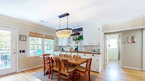 A spacious kitchen with a dining area, wooden flooring, and a chandelier. - Ocean-view dog-friendly home across street from beach with private pool, W/D, AC (Edisto Beach)