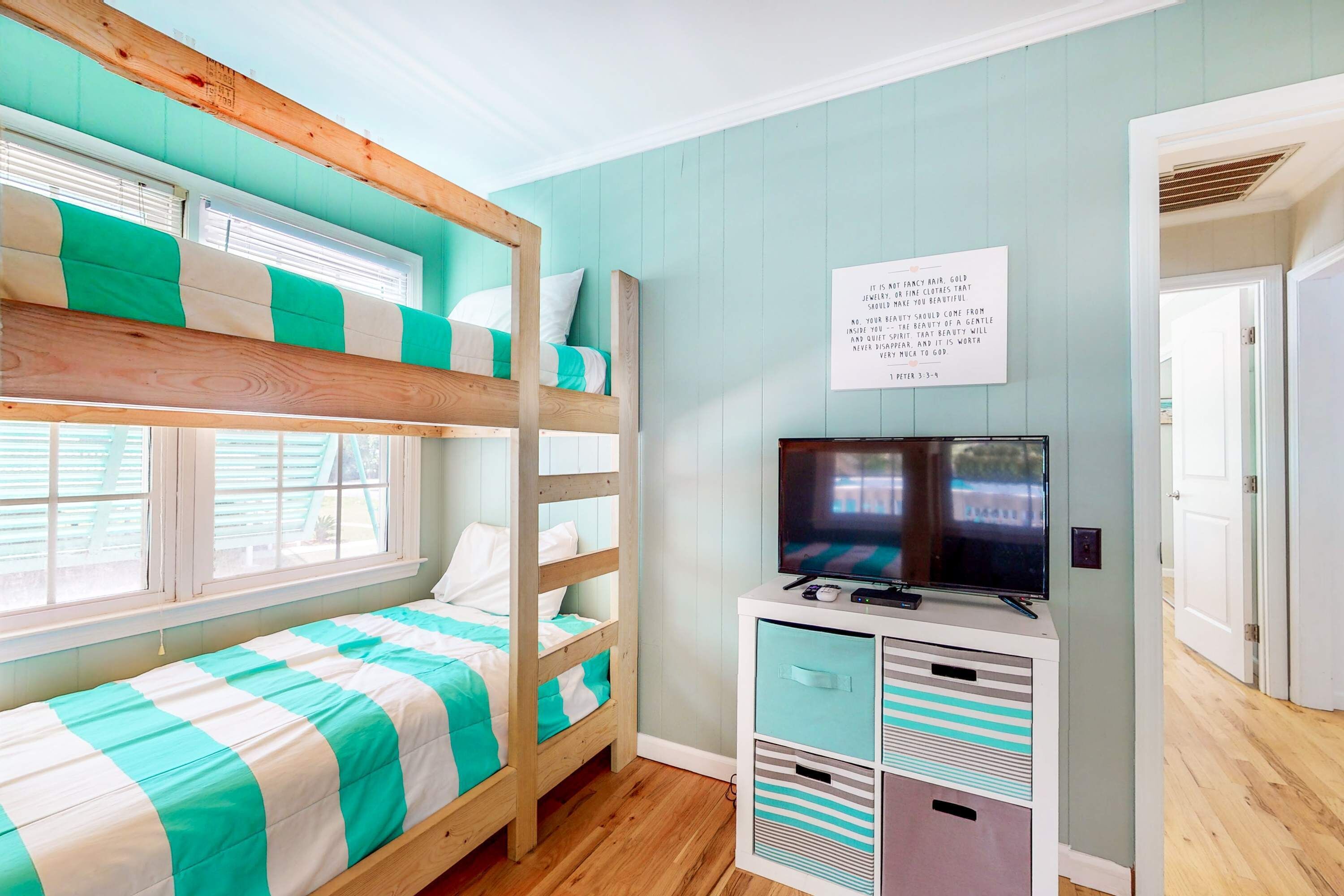 A bunk bed room with a TV and storage unit.
