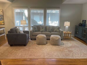 Ein Wohnzimmer mit einer Couch, Hocker, einem Couchtisch und einer Lampe.
