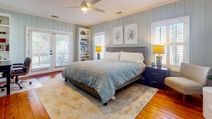A bedroom with a bed, a desk, a chair, a bookshelf, a nightstand, a lamp, and a ceiling fan. - Natural Wonder (Edisto Beach)