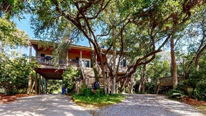 A two-story building with a covered porch and a gravel pathway leading to it. - Natural Wonder (Edisto Beach)