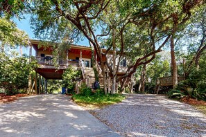 A two-story building with a covered porch and a gravel pathway leading to it. - Natural Wonder (Edisto Beach)