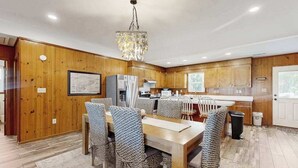 Eine moderne Küche mit Holzausstattung, einem Essbereich mit Tisch und Stühlen sowie einer Kristallleuchtre.