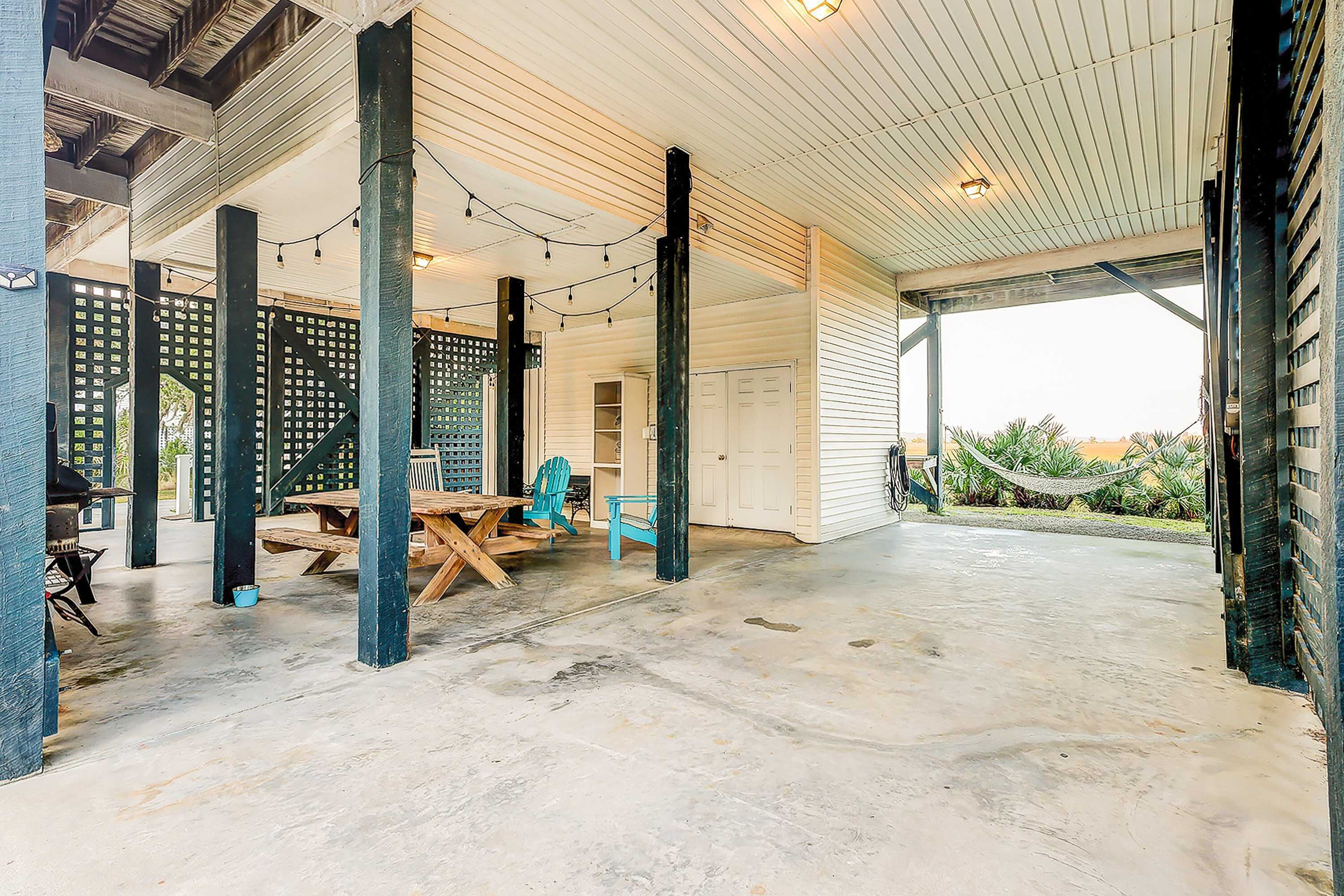 A covered outdoor area with a concrete floor, wooden furniture, and string lights.