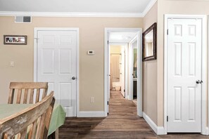 Un pasillo con suelo de madera, puertas blancas y paredes color crema.