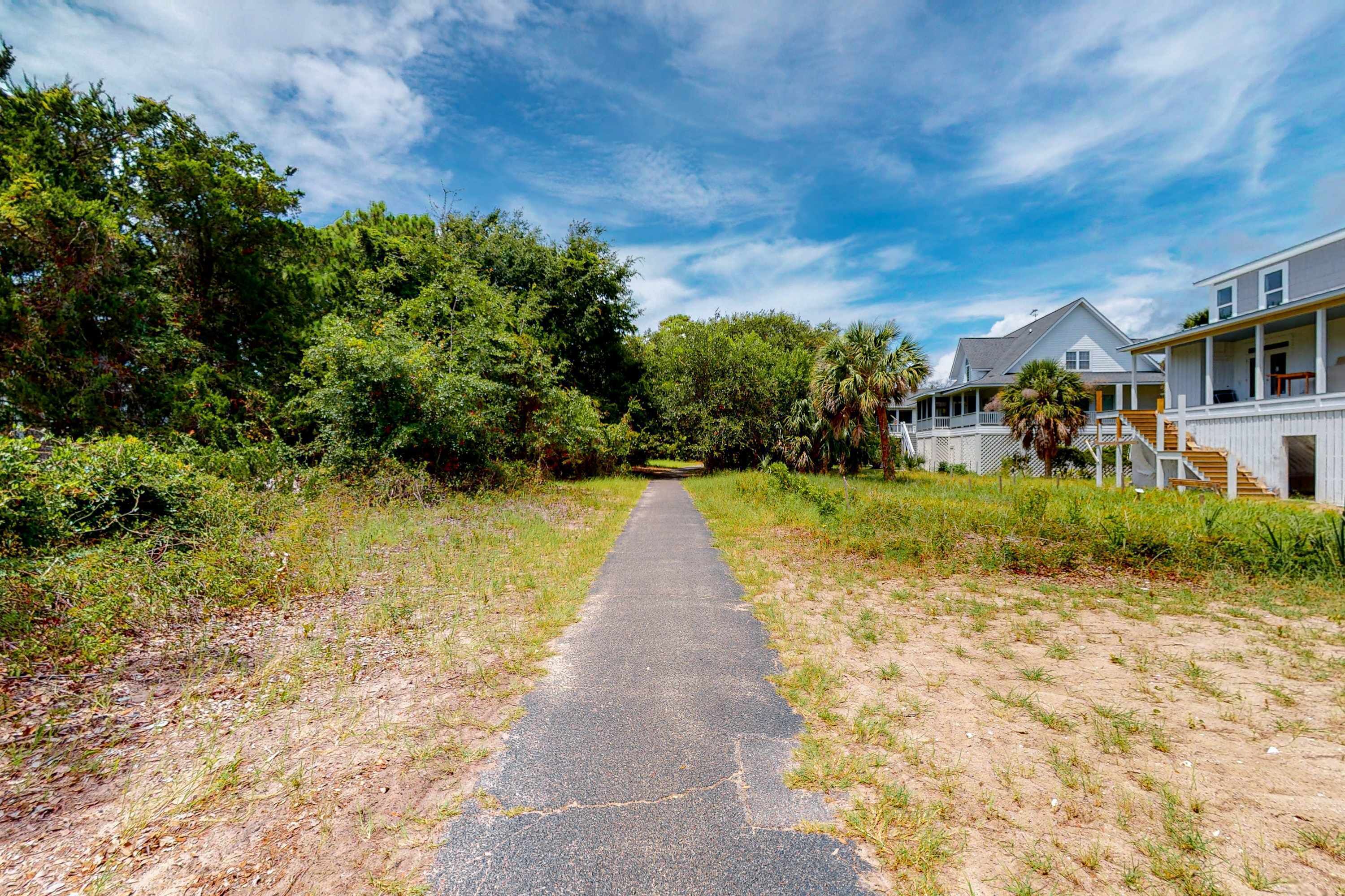 A pathway leading to a row of beachfront houses with a clear sky above.